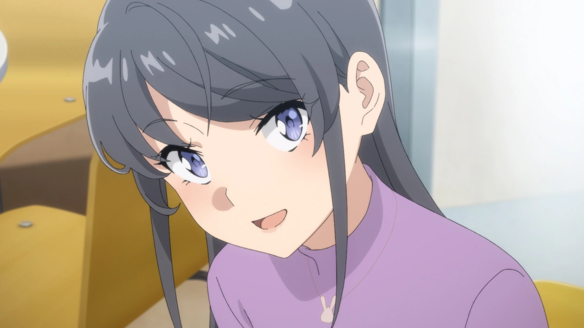 Mai Sakurajima con cabello largo y oscuro, una blusa morada y un collar de conejo, sonriendo levemente en un aula