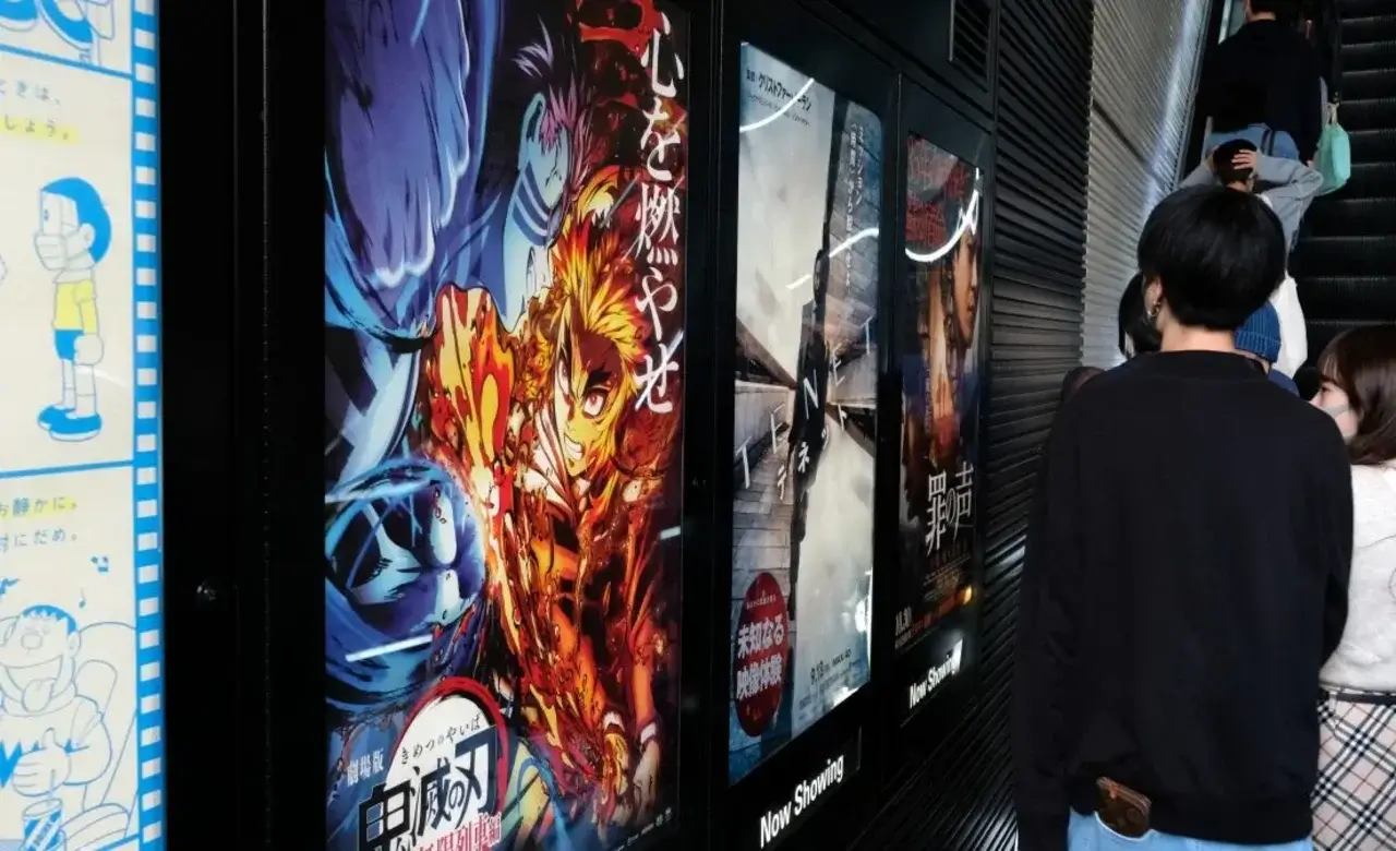 Personas pasando junto a carteles de películas de anime en un cine japonés