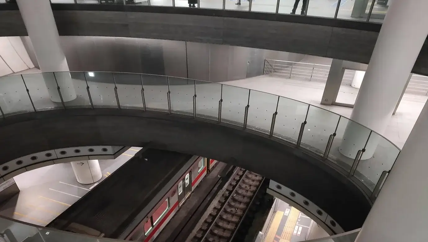Vista interior de los pasillos curvos y andenes de la estación de Shibuya con un tren en la vía, similar al escenario del Incidente de Shibuya en Jujutsu Kaisen