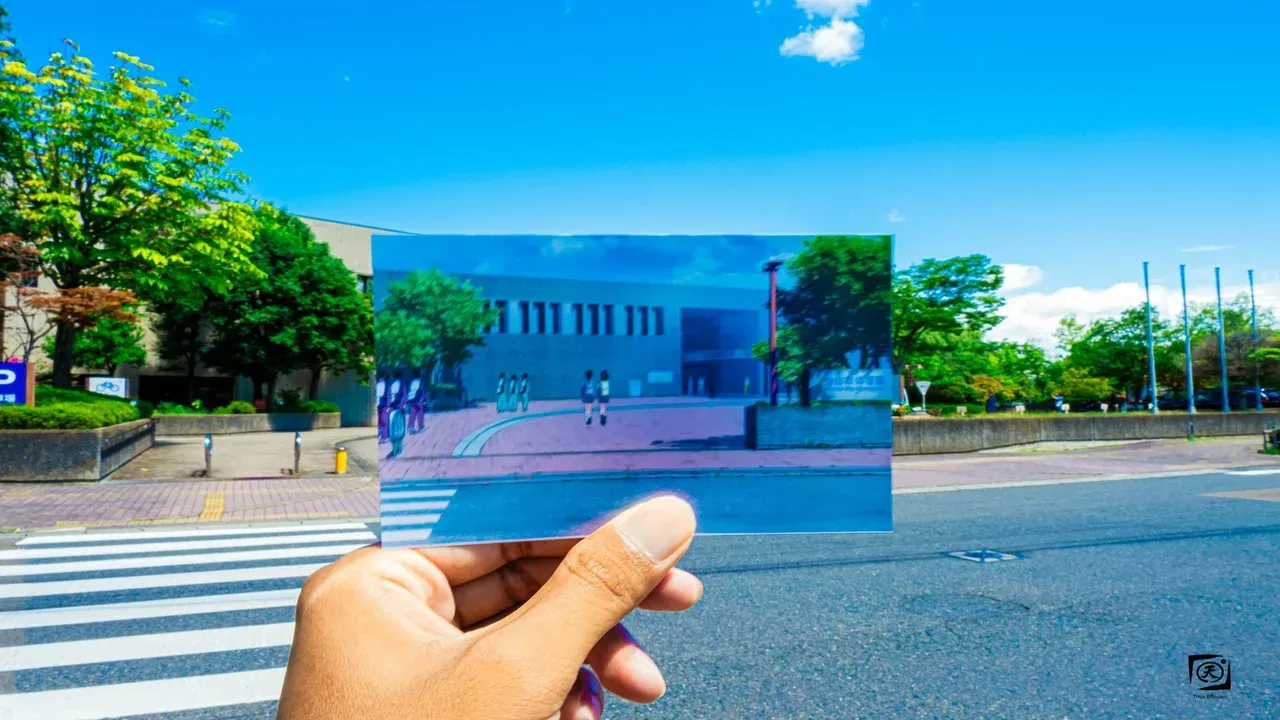 Fan sosteniendo una captura del anime Haikyuu frente al edificio real que inspiró la Preparatoria Aoba Josai en Sendai, Japón