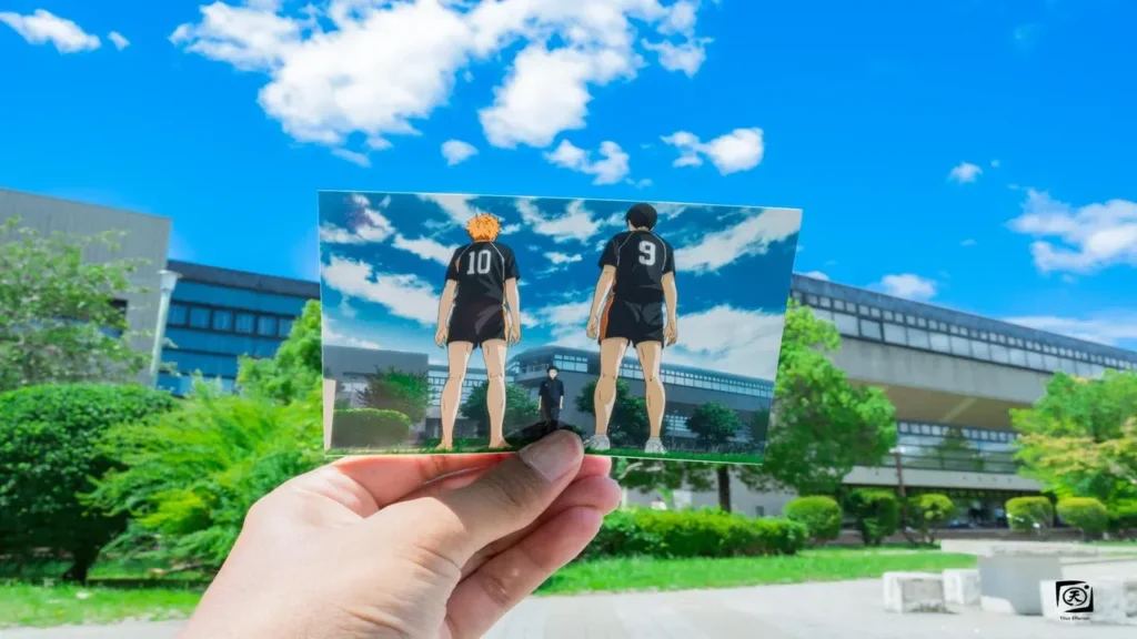 Fan sosteniendo una captura del anime Haikyuu frente a la localización real en Sendai, con Hinata y Kageyama de espaldas con los dorsales 10 y 9