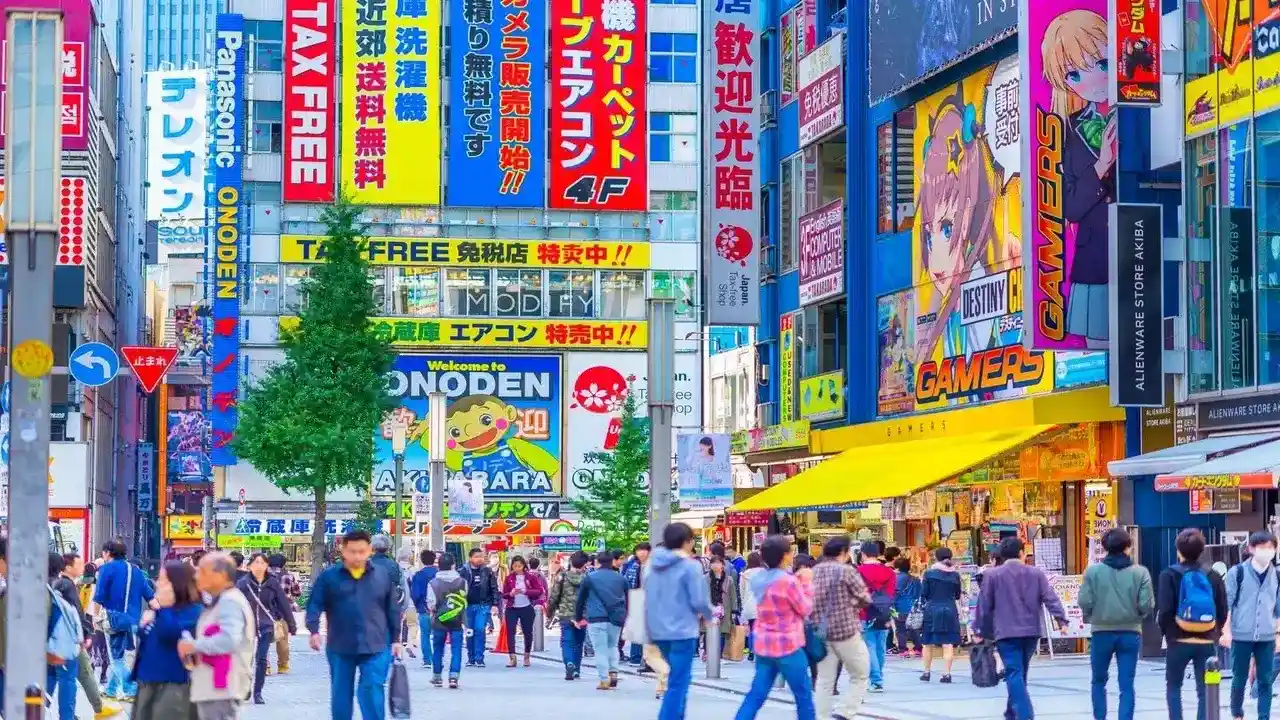Multitud de personas caminando por una concurrida calle peatonal en Akihabara, Tokio, rodeados de la famosa tienda Gamers y múltiples letreros de tiendas Tax-Free.