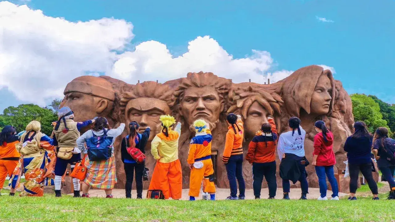 Visitantes disfrazados frente al mural de los Hokage en Nijigen no Mori, parque temático de anime en Awaji, Japón