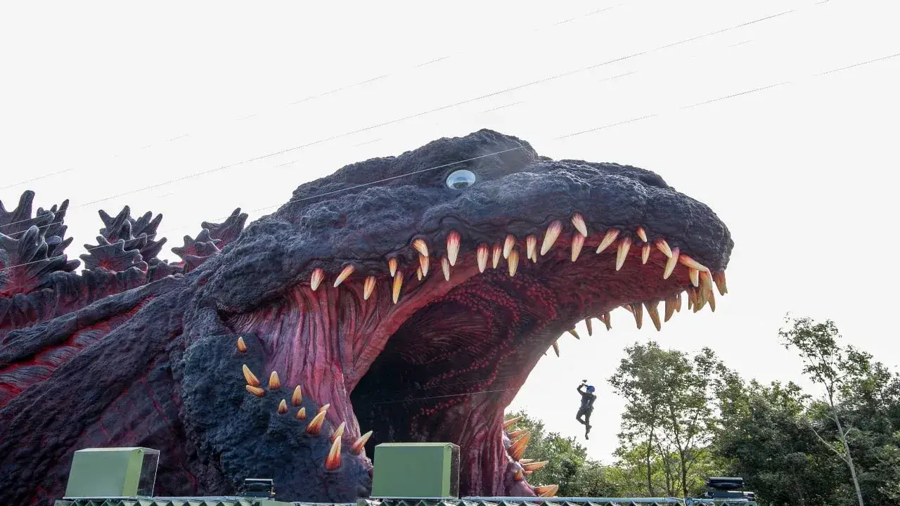 Visitante en tirolina lanzándose hacia las fauces de Godzilla en Nijigen no Mori, Awaji, Japón