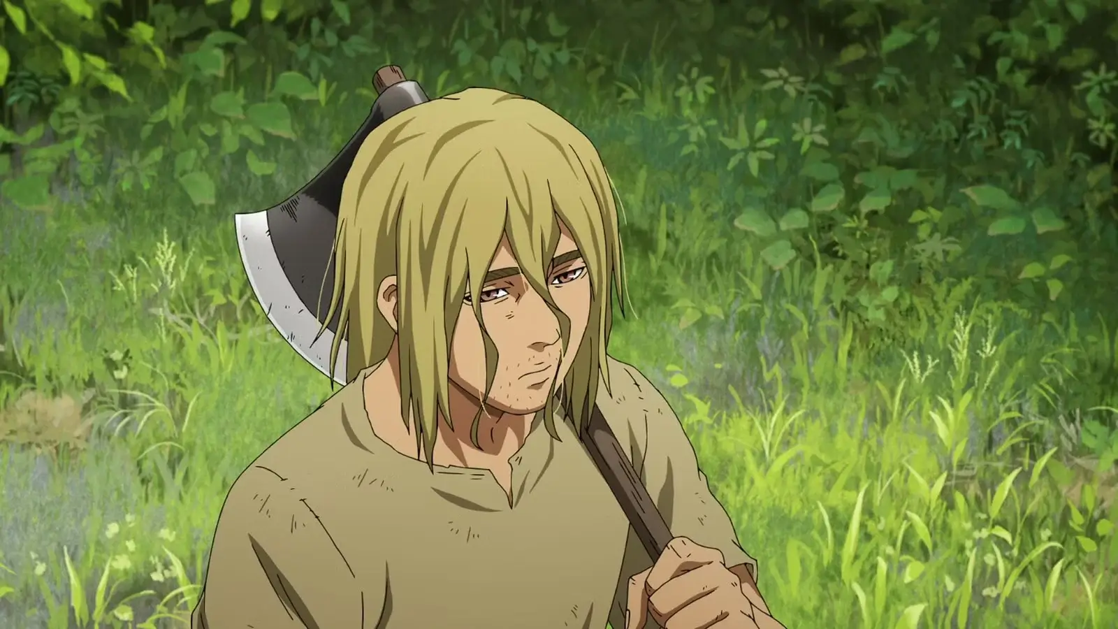 Thorfinn adulto cargando un hacha sobre su hombro mientras camina por un bosque verde