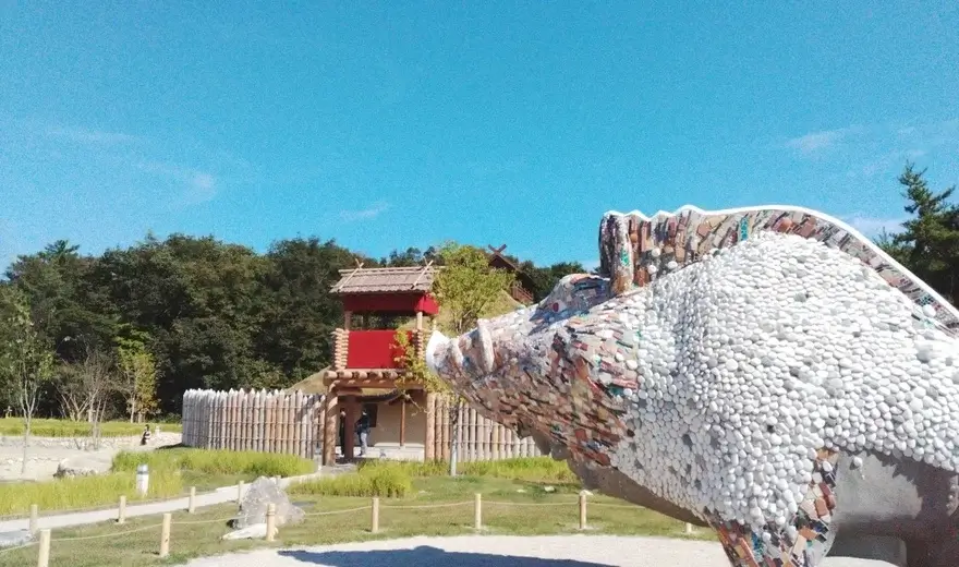Escultura de jabalí cubierta de mosaicos junto a la torre de madera de la Aldea Mononoke en Ghibli Park, inspirada en La Princesa Mononoke
